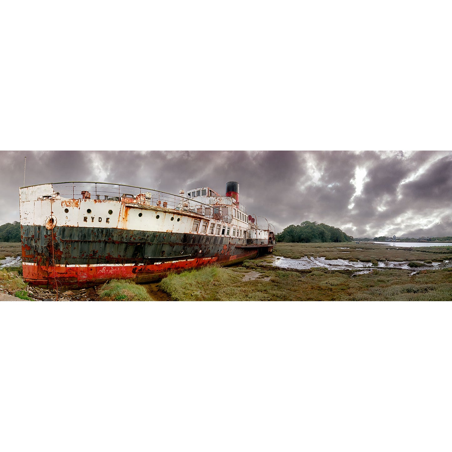 An old, rusting paddle steamer beached on a muddy riverbank under a cloudy sky on the Isle of Wight, captured in stunning detail by Available Light Photography's The Ryde Queen.