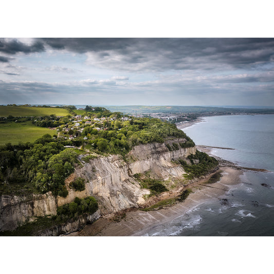 Aerial view of Luccombe coastal cliffside with a village overlooking a beach and the sea on the Isle of Wight by Available Light Photography.