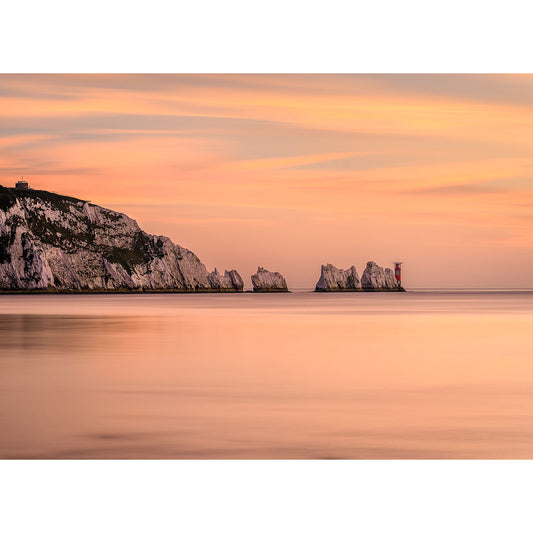 A serene sunset over a calm sea with a view of white chalk cliffs on the Isle of Wight and a distant lighthouse captured in "The Needles" by Available Light Photography.