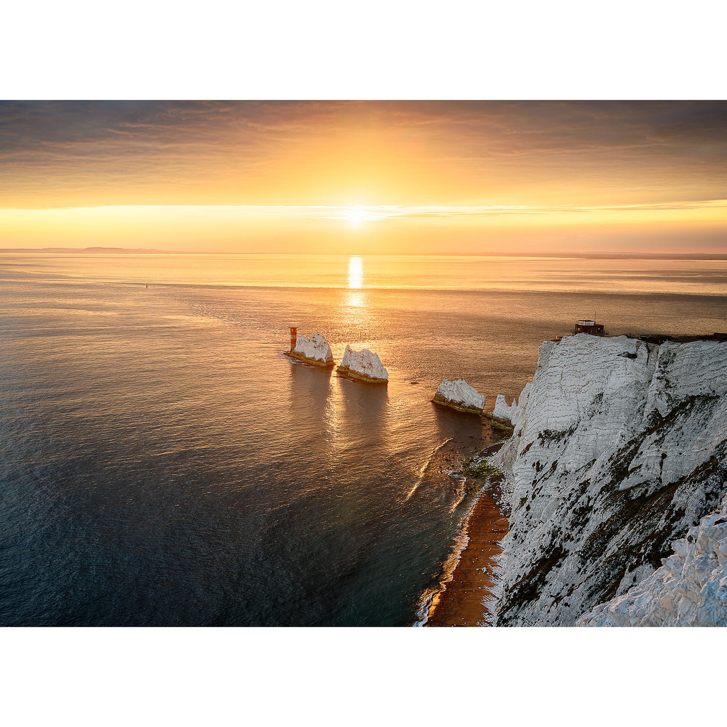 Sunset over the ocean with The Needles chalk cliffs on the Isle of Wight on the right and a ship passing by on the left, captured by Available Light Photography.