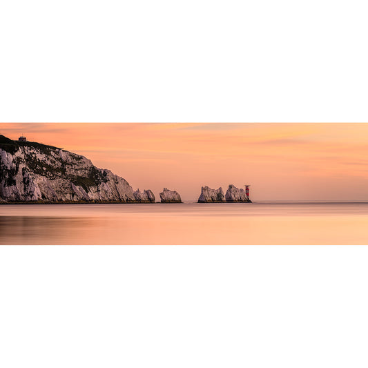 A tranquil sunset over a coastal landscape with cliffs and Isle rock formations extending into the sea captured by The Needles from Available Light Photography.