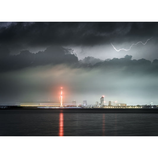 A city skyline at night under stormy skies with Lightning over Spinnaker Tower in the distance and reflections on the waters of the Isle. (Photograph by Available Light Photography)