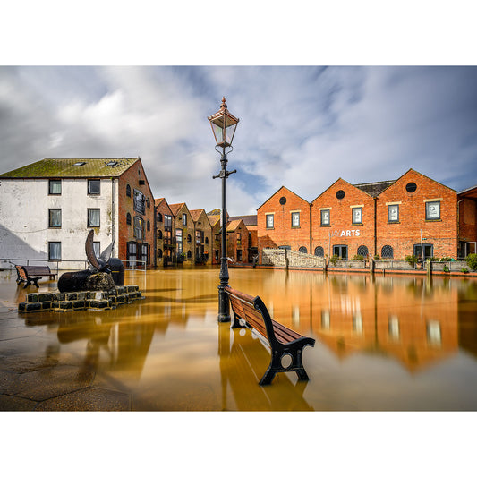 Flooded urban area with buildings, a lamppost, and a bench partially submerged in water at Newport Quay on the Isle of Wight by Available Light Photography.