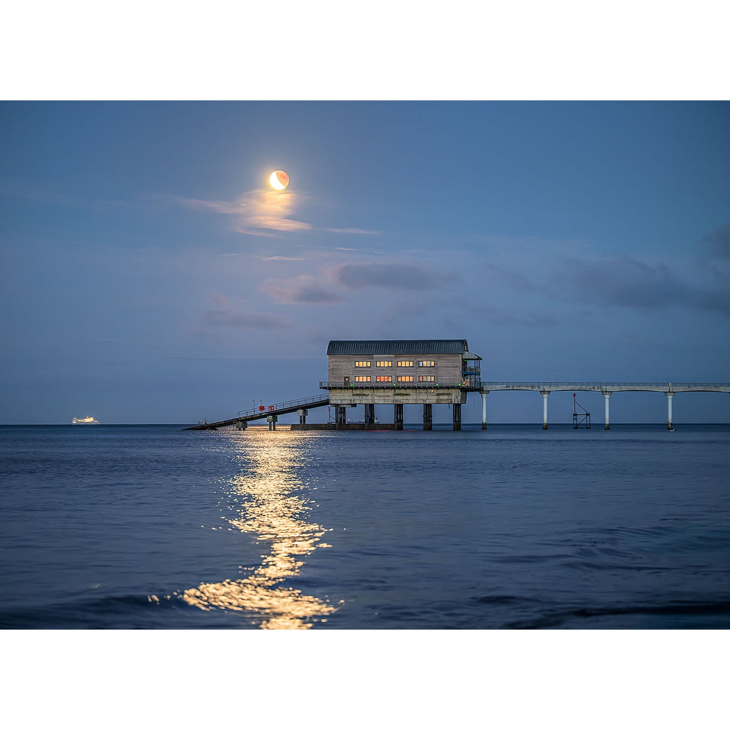 Lunar Eclipse, Bembridge Lifeboat Station by Available Light Photography captures the station on stilts over calm dusk waters, with a bright moon and shimmering reflections in the tranquil sky and sea.