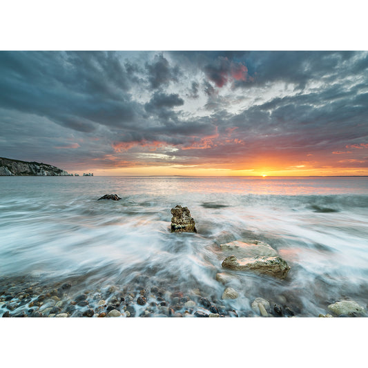 Sunset over a rocky shore with the tide coming in under a dramatic sky in Alum Bay by Available Light Photography.