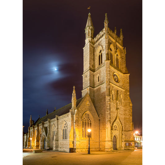 An illuminated St. Thomas Church at night with a crescent moon in the sky on the Isle of Gascoigne by Available Light Photography.