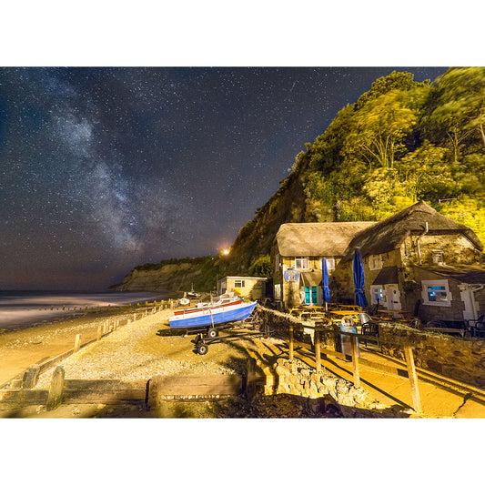 A Milky Way sky over a rustic hut by the Wight sea with a boat on a slipway, captured by Available Light Photography.