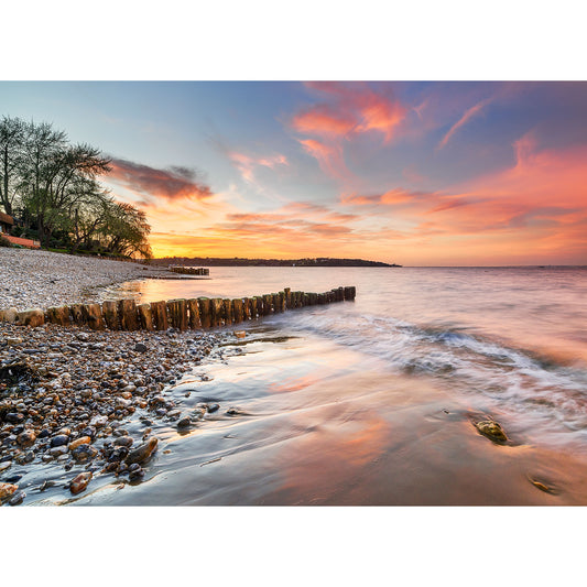 Sunset hues over Bembridge Beach on the Isle with gentle waves and a wooden breakwater by Available Light Photography.