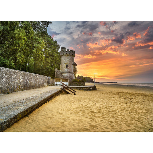 Sunset view at a beach with the Appley Tower and stone wall, leading to a jetty with a bench under an orange sky on Gascoigne Isle by Available Light Photography.