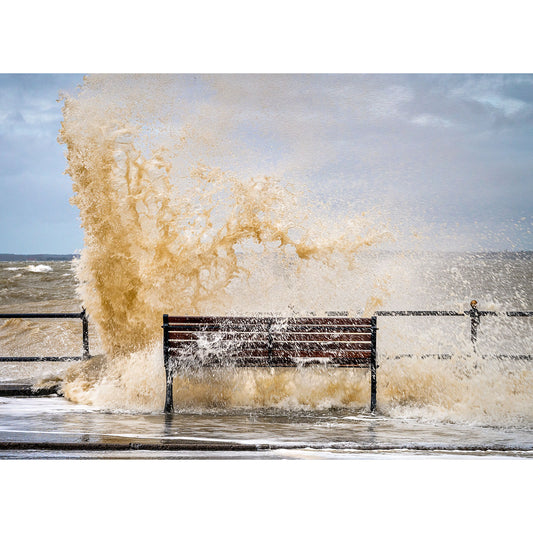 A 'Best seat in the house' bench on the Isle of Wight seafront promenade being engulfed by a large, dramatic wave by Available Light Photography.