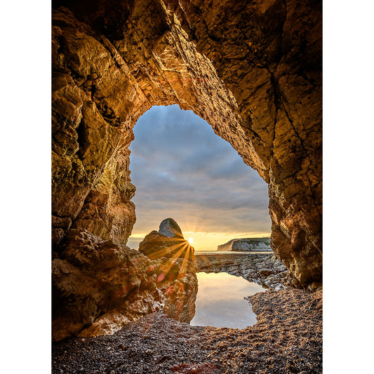 Sunset viewed through a natural archway on the Isle of Wight's rocky shore in the In the Caves, Freshwater Bay photograph by Available Light Photography.