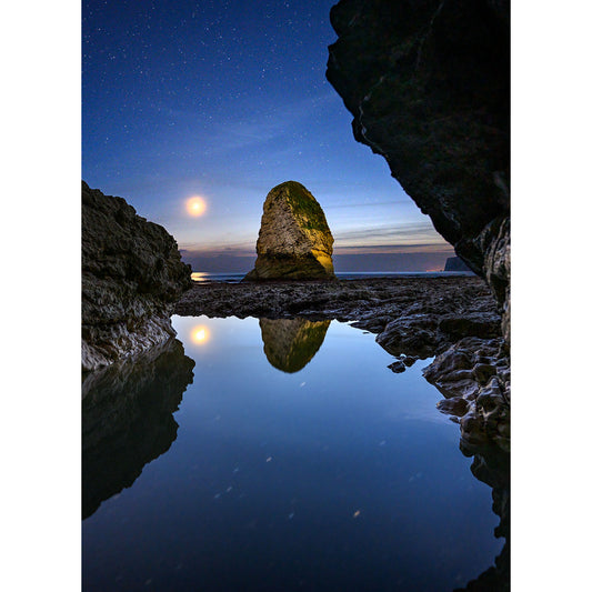 A serene night scene with Moonset at Freshwater Bay reflected in still water, framed by shadowed cliffs under a starry sky, captured by Available Light Photography.