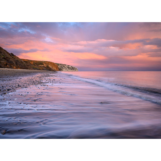 Sunset hues paint the sky over a serene beach on the Isle of Wight, with Culver Cliff in the distance captured by Available Light Photography.