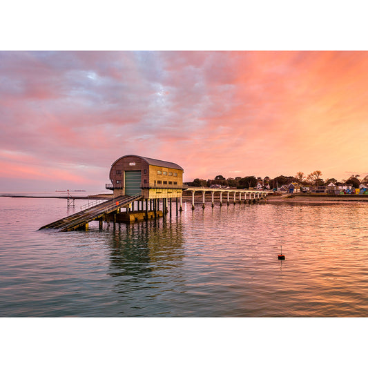 Coastal structure on stilts extending into calm waters under a dramatic sunset sky by Available Light Photography featuring the Bembridge Lifeboat Station.