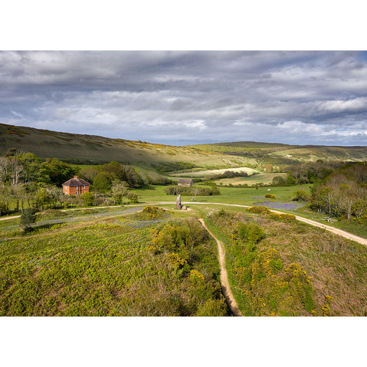 Pastoral landscape with a winding path leading to a Longstone house amidst lush greenery under a cloudy sky captured by Available Light Photography.