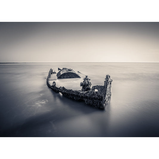 A shipwreck SS Carbon protrudes above a calm sea surface near the Isle of Wight in a tranquil long-exposure photograph by Available Light Photography at Compton Bay.