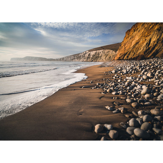 A Compton Bay shoreline with waves gently lapping at the beach, with towering cliffs under a clear sky on the Isle of Wight by Available Light Photography.