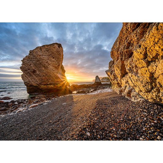 Sunset at Freshwater Bay on the Isle of Wight with the sun peeking through large stone formations by Available Light Photography.