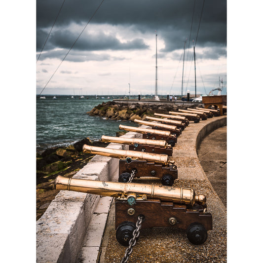Row of Cowes cannons overlooking the sea under a cloudy sky at Gascoigne.