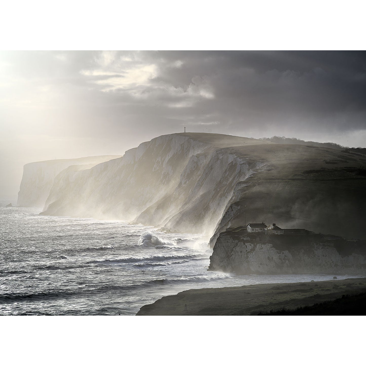Lonely Tennyson Down by the sea on the Isle of Wight, under the shadow of towering cliffs, with waves crashing onto the shore under a dramatic sky captured by Available Light Photography.