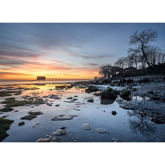 Sunrise at Bembridge Beach with a pier in the background and reflective tidal pools in the foreground, captured beautifully by Steve Gascoigne for Available Light Photography.