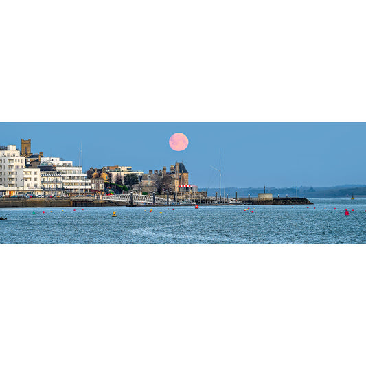 A Moonset over Cowes with buildings and anchored boats visible at dusk in the coastal town of Wight, captured by Available Light Photography.