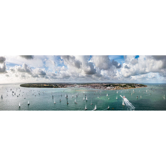 A panoramic view of the Round the Island Race sailing regatta with numerous boats on the vast waters near Cowes and East Cowes, under a sky with scattered clouds, captured by Available Light Photography.