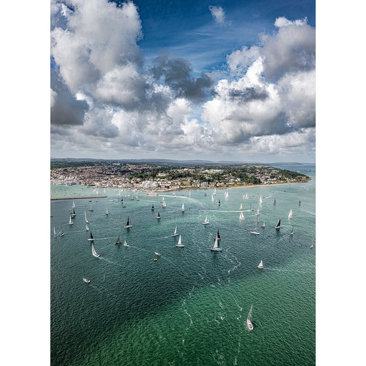 Aerial view of the Round the Island Race, Cowes sailing regatta with numerous boats scattered across a wide expanse of water near the Isle of Wight under a partly cloudy sky by Available Light Photography.
