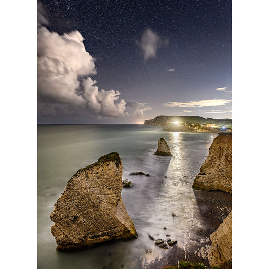 A serene night sky over a coastal landscape with illuminated sea stacks and a blanket of stars, reminiscent of a Available Light Photography Freshwater Bay painting.