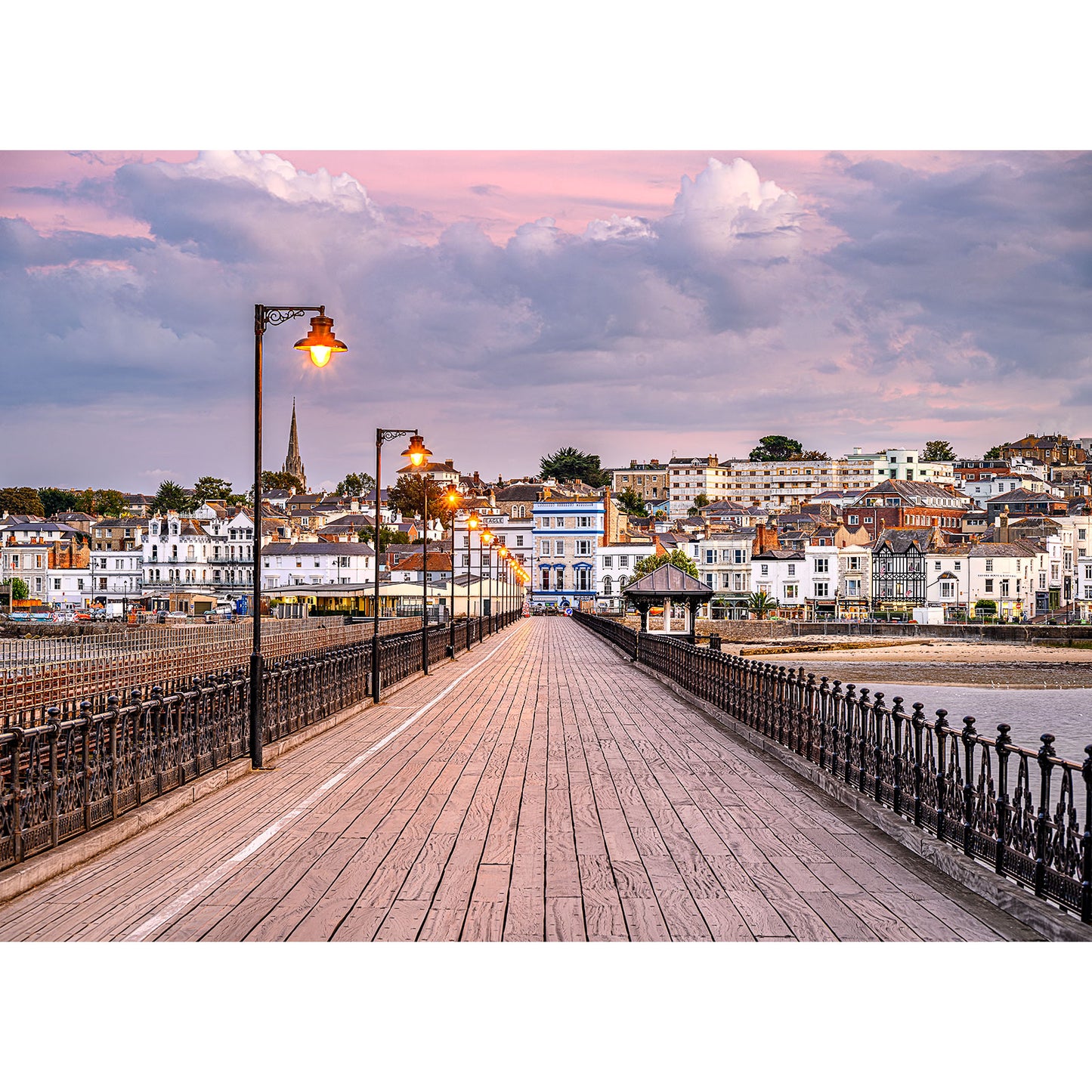 Ryde Pier extending towards a coastal town with illuminated street lamps at dusk, overlooking the tranquil Gascoigne waters by Available Light Photography.