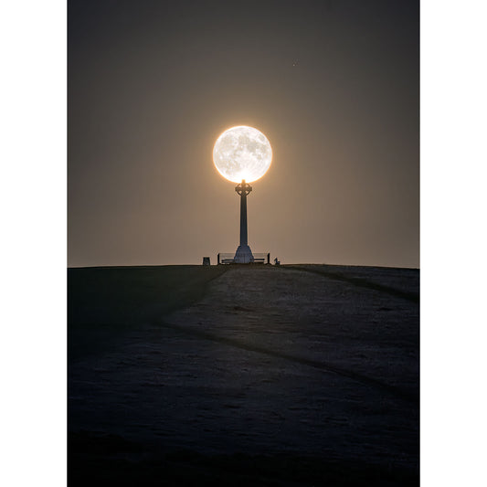 A Moonrise over Tennyson Monument from Available Light Photography aligned directly above a monument on the Isle of Wight at twilight.
