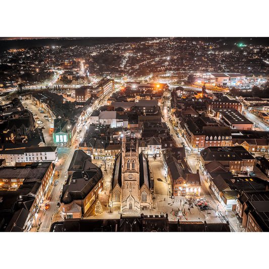 Aerial night view of a city with illuminated streets and a prominent church tower at the center on the Isle of Newport by Available Light Photography.