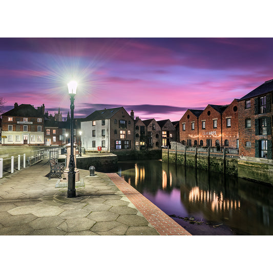 Twilight over a tranquil riverside with historic brick buildings and a glowing streetlamp, cast in the haunting aura of Newport Quay by Available Light Photography.