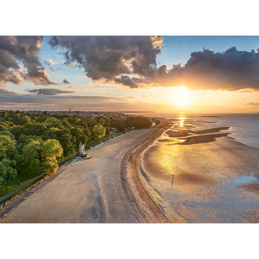 Aerial view of Appley Beach at sunset, featuring a sunlit beach, trees, and a cloud-covered sky on the Isle of Wight by Available Light Photography.