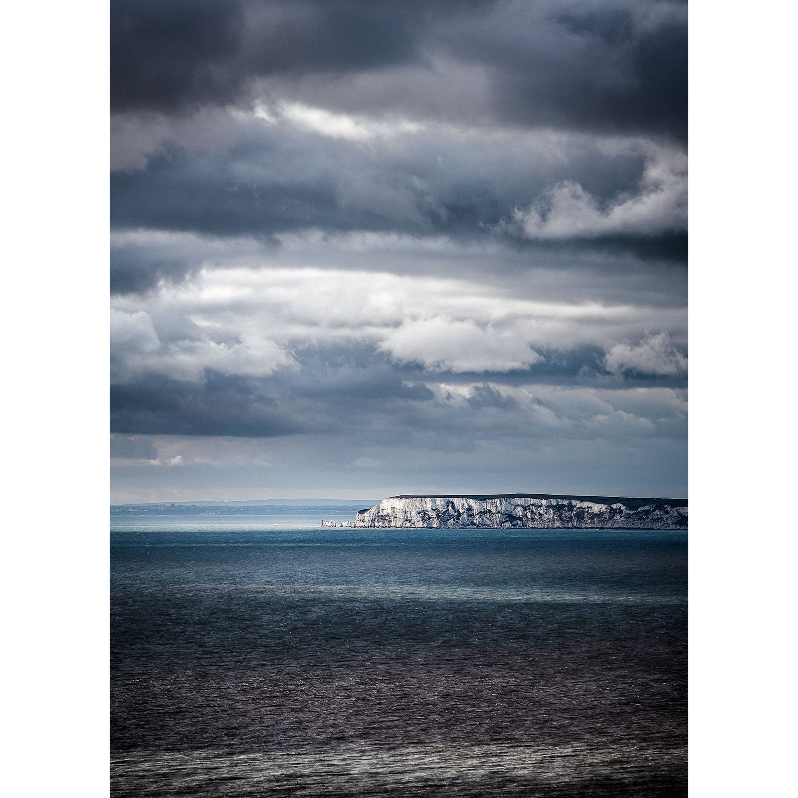 A dramatic view of The Needles cliff coastline on the Isle of Wight under overcast skies by Available Light Photography.