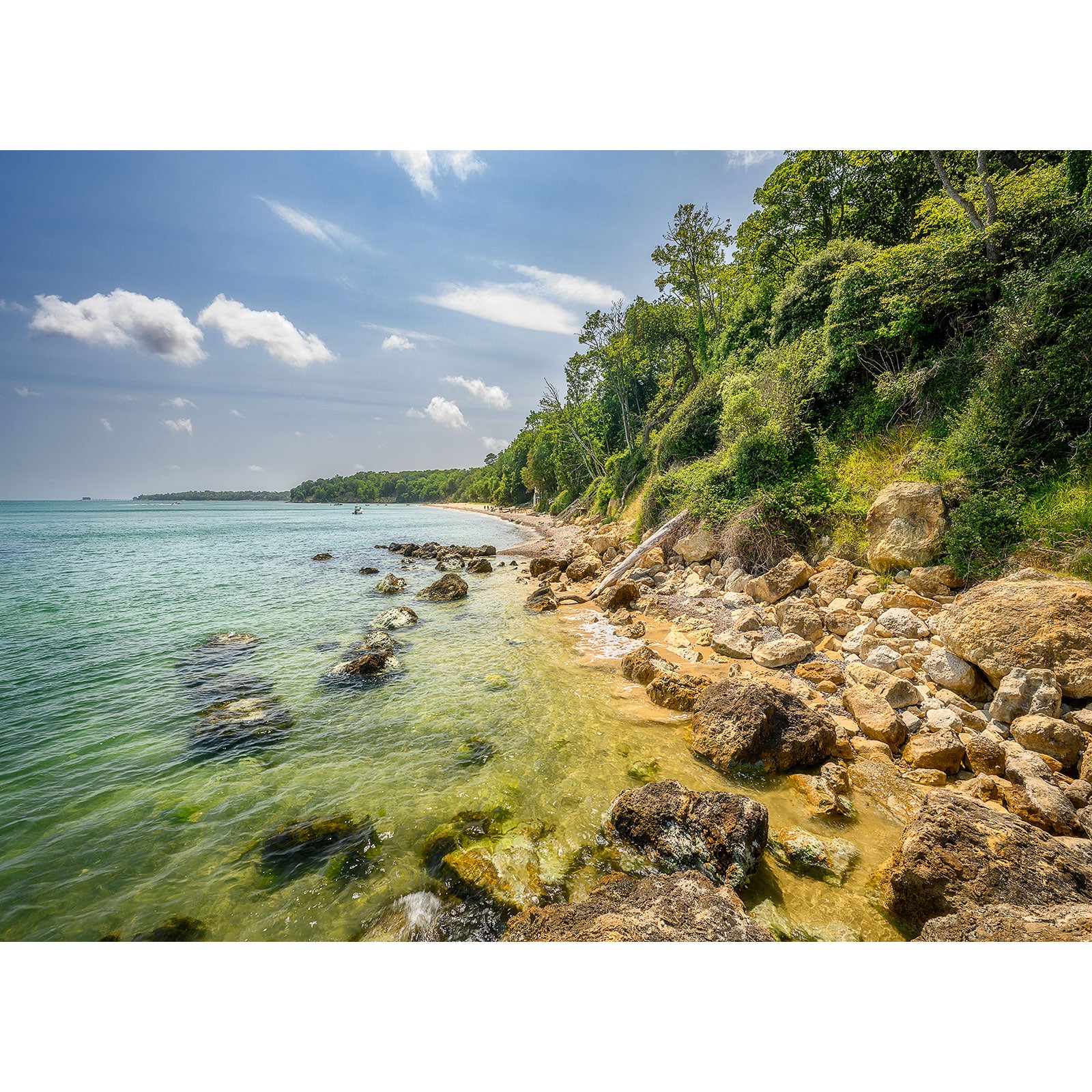 A serene coastline on the Isle of Wight with a rocky shore under a clear blue sky captured by Available Light Photography's Priory Bay.
