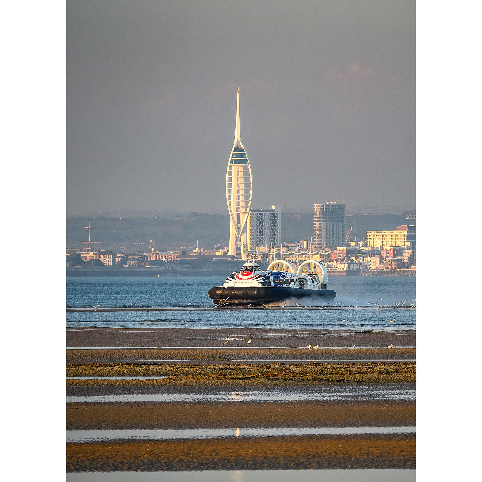 A Incoming Hovercraft travels across the water in the foreground with the iconic Spinnaker Tower in the background, near the Isle of Wight by Available Light Photography.