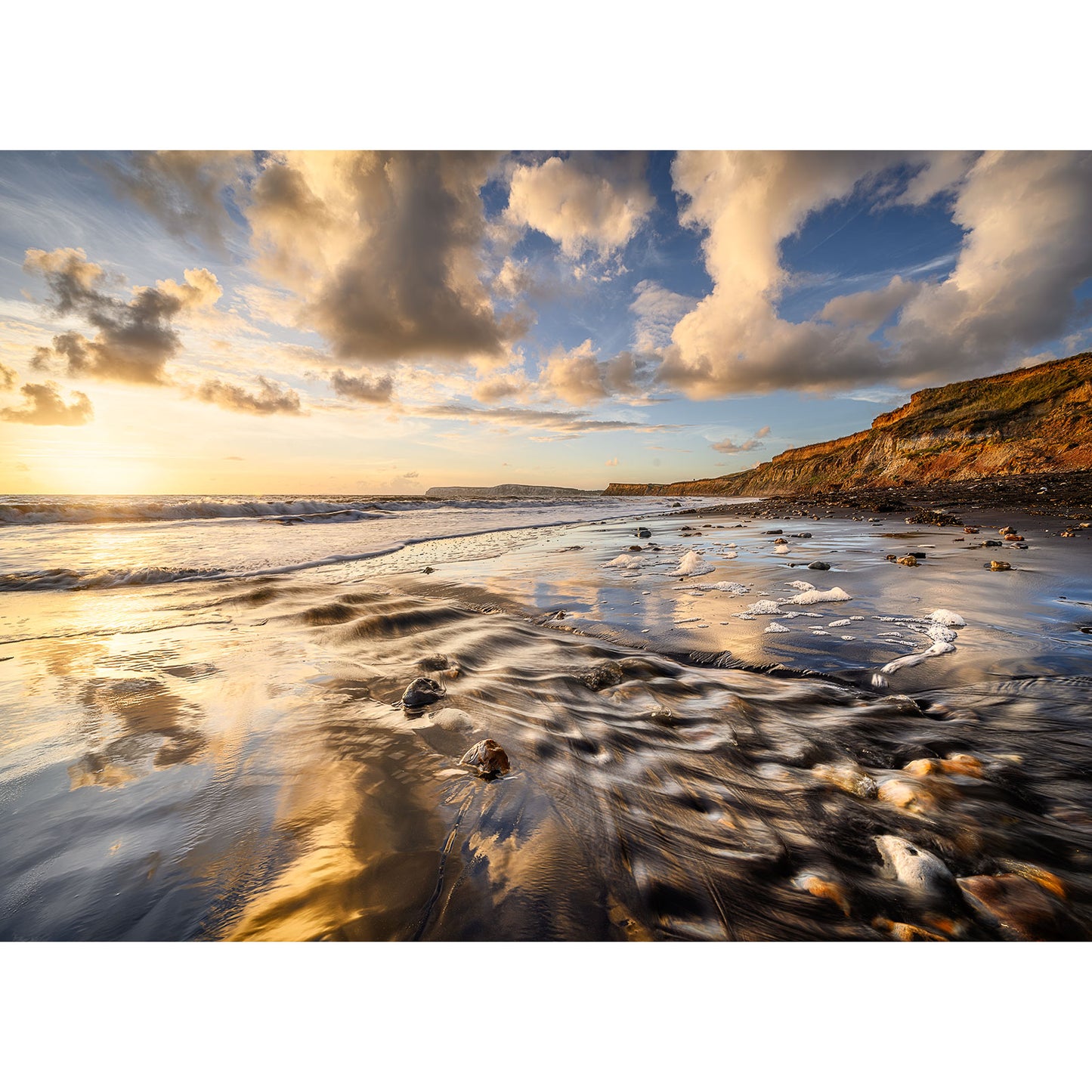 Brook Bay sunset reflecting on a rippled beach with cliffs in the distance on the Isle of Wight by Available Light Photography.