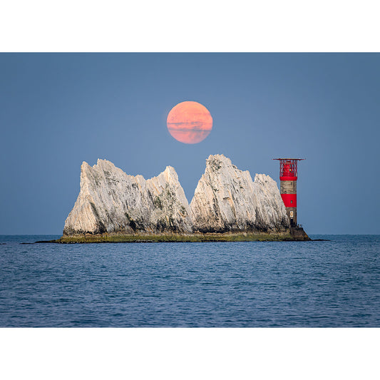Moonset over The Needles rising over a rocky isle with a red lighthouse at dusk by Available Light Photography.