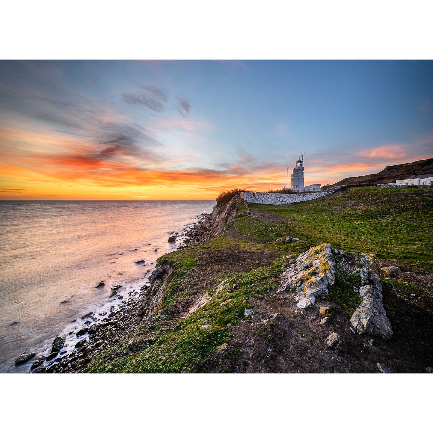 Spectacular St. Catherine's Lighthouse on a coastal cliff at sunset by Available Light Photography.