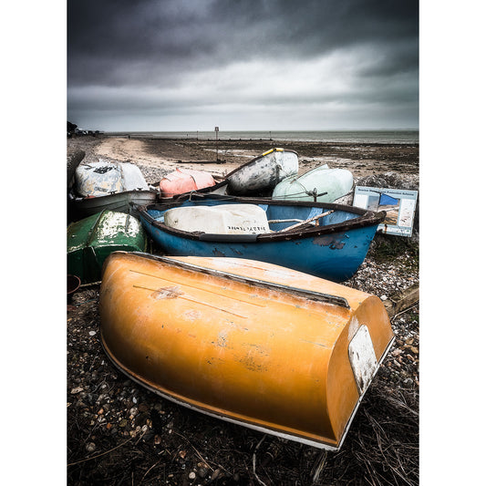 Overturned boats on a pebble beach under overcast skies, captured in Image number A12345 by Seaview Duver from Available Light Photography.