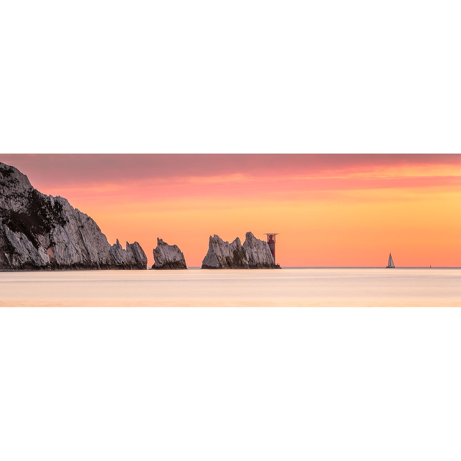 A serene sunset over a calm sea with silhouettes of cliffs and a distant sailboat on the horizon. Image number: 2828 The Needles by Available Light Photography.