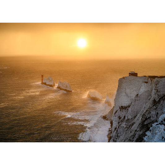 Sunset over rough seas with waves crashing against large chalk cliffs and The Needles, under a golden sky taken by Available Light Photography.