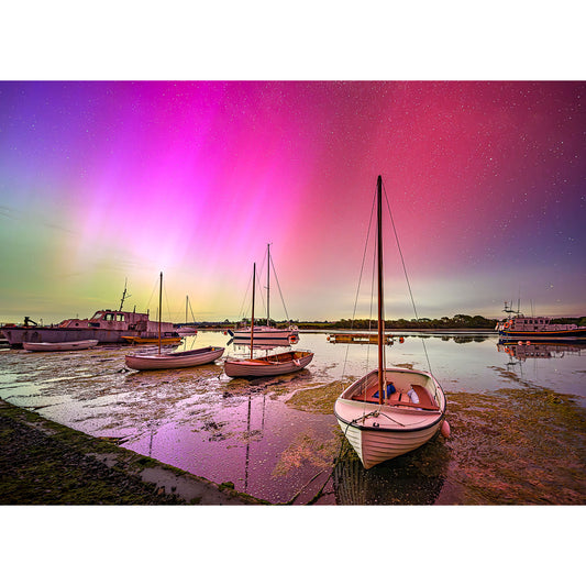 Sailboats moored on a low tide shore under a vibrant The Northern Lights-lit sky at dusk. (Available Light Photography)