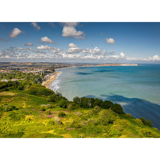 Sandown Bay from Luccombe by Available Light Photography features green hills, a sandy shoreline, and a coastal town under a blue sky with clouds.