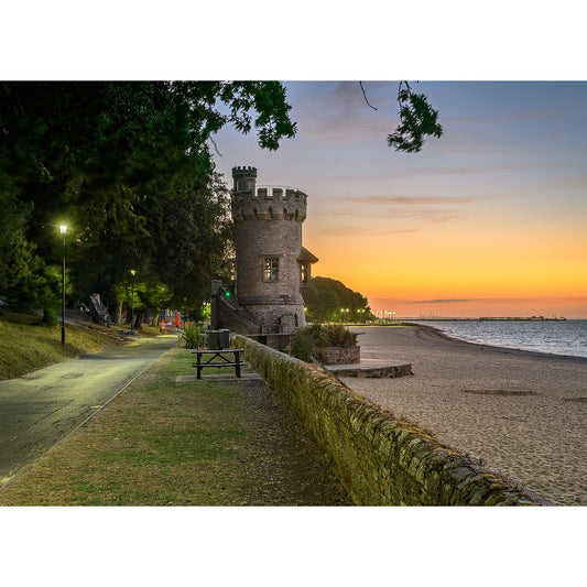 Appley Tower by Available Light Photography captures a stone tower beside a sunset beach, with a winding path, trees, glowing lamplights on the left, and calm water on the right.