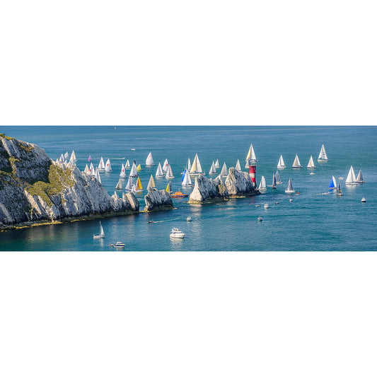 Sailboats compete in the Round the Island Race, captured by Available Light Photography as they sail past The Needles' white rocks and lighthouse on a calm blue sea under clear skies.