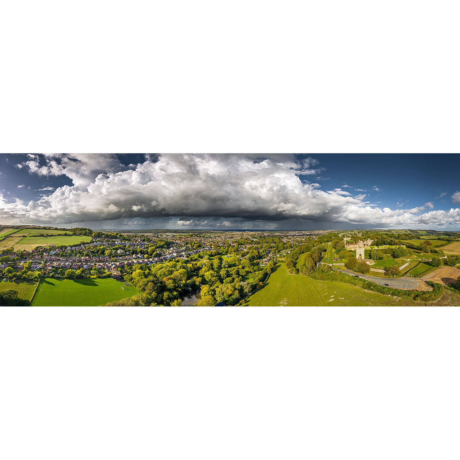 Aerial view of Carisbrooke’s historic building under swirling storm clouds, surrounded by green fields—Incoming Storm, Carisbrooke by Available Light Photography.