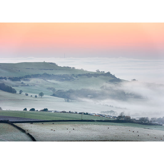 Overlooking Wroxall and Appuldurcombe by Available Light Photography captures rolling hills and misty fields at sunrise, with pastel orange and pink skies creating a serene, atmospheric landscape.