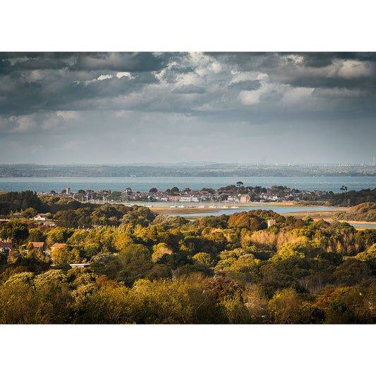 Yarmouth from Tennyson Down by Available Light Photography features a landscape view of a coastal town with houses, trees, and water beneath a cloudy sky.
